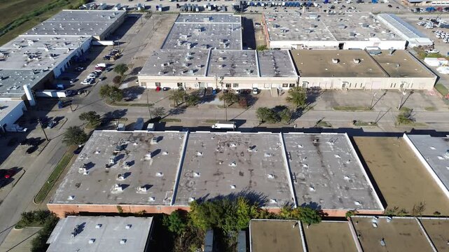 Dallas warehouse district showing flat-roof buildings, industrial rooftop HVAC, truck docks, structured road grid with dense trailers hub and greenbelt buffer near floodplain zoning boundary