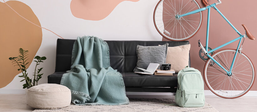 Stylish sofa and bicycle near color wall in interior of living room