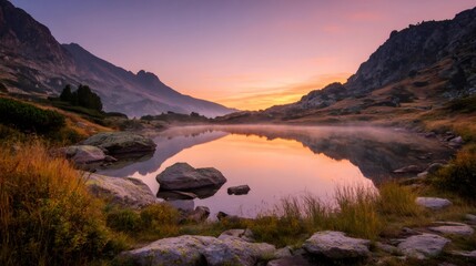 Naklejka premium Mountain lake reflecting early morning light with mist covering water surface and surrounding autumn landscape