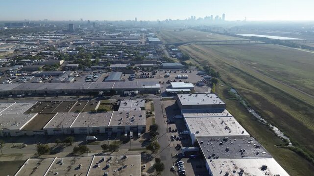 Grassy vacant land near Trinity River Trail, Walton Walker Blvd transportation hub with overflow trailer storage, flatbeds, enclosed warehouse units, dense trailer rows, downtown Dallas skylines