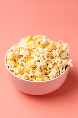 Bowl with crispy popcorn on pink background