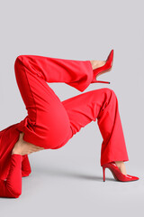 Female legs in red high heels on grey background