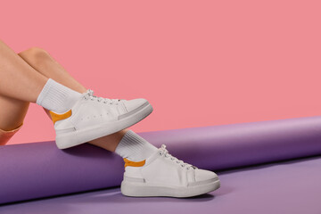 Female legs in stylish sneakers and socks on color background