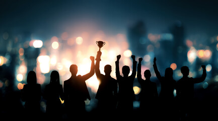 Silhouettes of business people celebrating success and teamwork against a city nightscape with one person holding a trophy high symbolizing achievement and unity.
