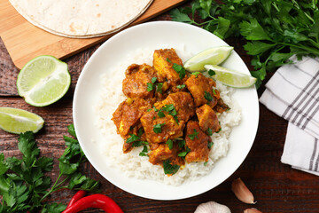 Chicken tikka masala with rice served on wooden table, flat lay