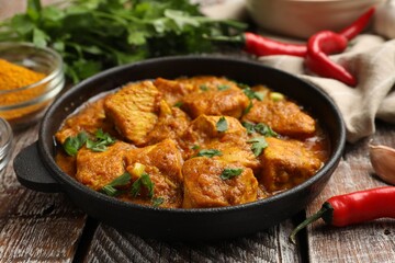 Chicken tikka masala with spices on wooden table, closeup