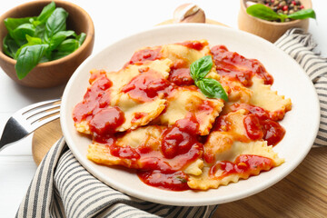 Delicious ravioli with tomato sauce and basil served on white wooden table, closeup
