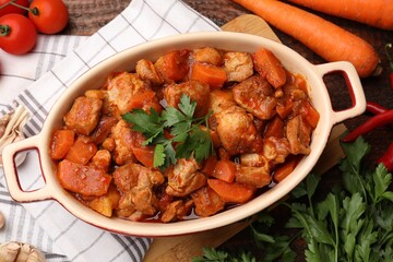 Delicious cooked stew in baking dish and ingredients on table, flat lay