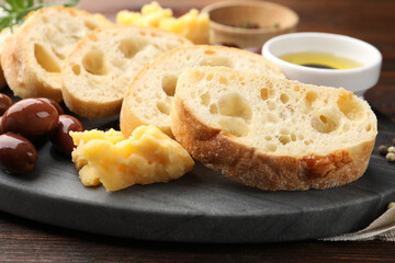 Pieces of fresh ciabatta, olives and cheese on wooden table, closeup
