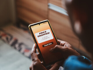 Man phone displaying price dropped real-time notifications for a specific item. Online shopping, artificial intelligence technology applications in e-commerce concept. S