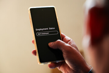 Man using smartphone to fill out job description employment status as self-employed. Back view, selective focus. 