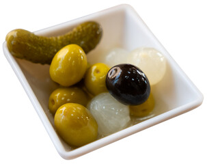 Bowl is filled with pickled vegetables - olives, small onions, gherkins. Piquant appetizer, antipasto, vegetable addition to main course. Isolated over white background