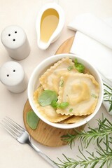 Delicious ravioli with basil served on light table, flat lay