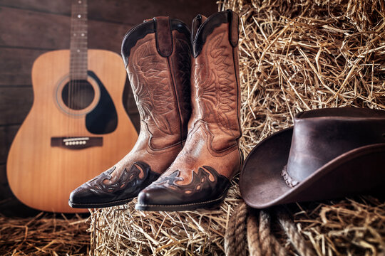 Cowboy hat guitar and boots in barn, country music festival live concert or rodeo background