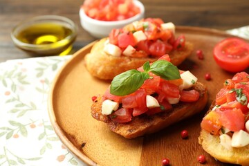 Tasty bruschettas with tomatoes, mozzarella cheese and basil served on table, closeup