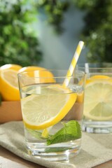 Refreshing water with lemons and mint on table outdoors, closeup