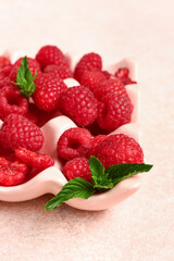 Ice cube tray with fresh raspberries and mint on light background