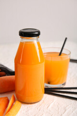 Glass and bottle of fresh carrot juice on white background