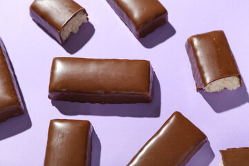 Tasty chocolate covered coconut candies on lilac background