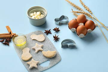 Composition with raw cookies, ingredients and cutters on color background