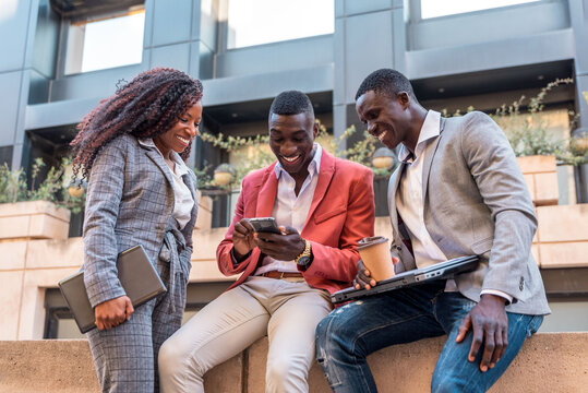 Group of multiracial business people using mobile phone outdoors and smiling