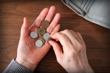 Fototapeta premium Close-up of senior's hand holding coins, cost of living and inflation concept
