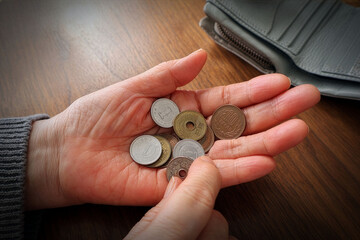Close-up of senior's hand holding coins, cost of living and inflation concept