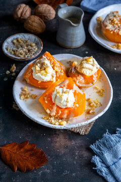 Turkish pumpkin dessert garnished with clotted cream, walnuts and tahini on a white plate from front view.