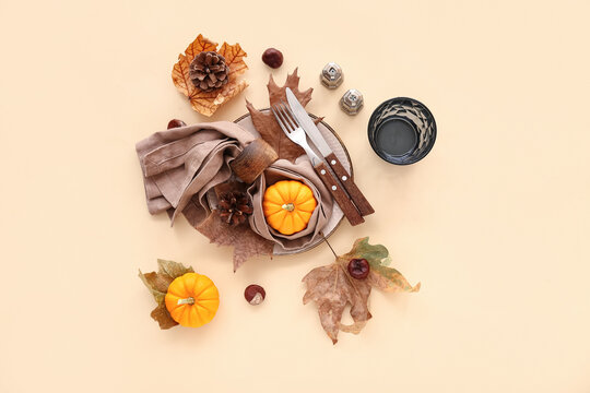 Beautiful autumn table setting with pumpkins and leaves on beige background