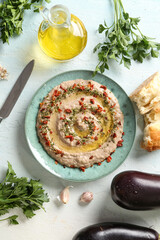Plate of tasty baba ghanoush with ingredients on white background