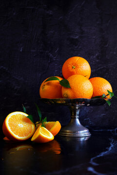 Classic navel oranges on stand, against a black marble background.