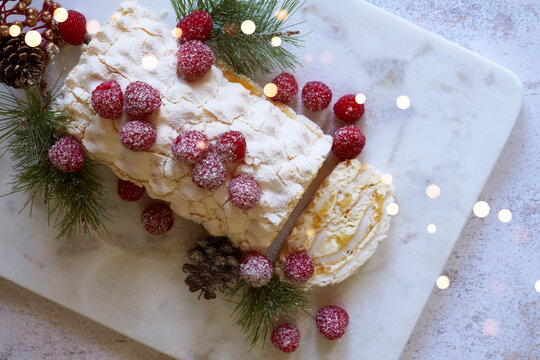 Christmas Buche de Noel White Yule Log Cake with Bokeh Lights on White Marble Board.
