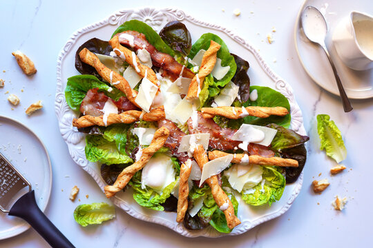 Classic Caesar Salad with Lettuce Greens, Grilled Bacon, Poached Eggs, Parmesan Cheese, and Pastry Crouton Twists.