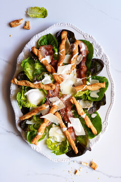 Classic Caesar Salad with Lettuce Greens, Grilled Bacon, Poached Eggs, Parmesan Cheese, and Pastry Crouton Twists.