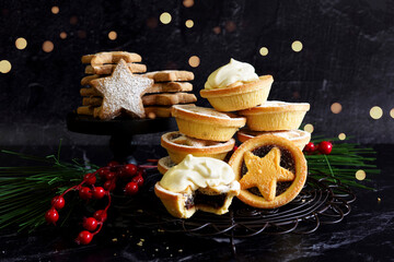 Fruit mince pies and star shape shortbread biscuits cookies in festive holiday background setting.