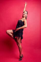 Female dancer posing gracefully in studio with red background
