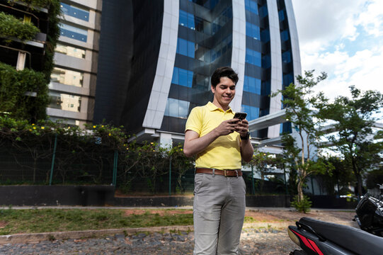 Connected urban professional using smartphone beside contemporary office tower