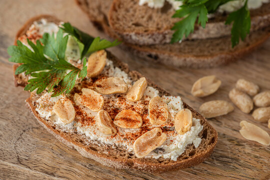 Open sandwich with cheese spread, peanuts and parsley on spelt bread