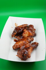 Crispy Grilled Chicken Wings on White Plate – Fast Food Photo on Green Background