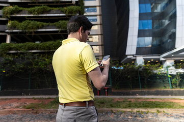 Modern business professional texting on phone beside eco friendly building