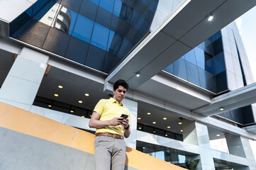 Focused professional reading messages on phone outside modern offices