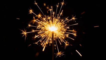 A vibrant sparkler bursts with golden sparks against a dark background, creating a dazzling display of light and motion.