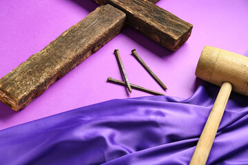 Wooden cross with purple cloth, hammer and nails on color background. Good Friday concept