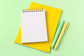 School notebooks and pens on green background