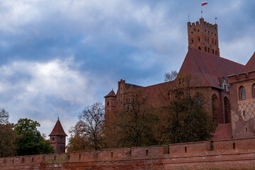 Malbork Castle red brick walls and keep above autumn trees in Poland © Earthly Shots
