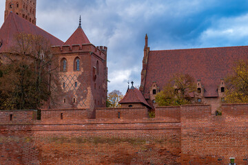 Malbork Castle's red brick walls and turrets rise behind ramparts © Earthly Shots