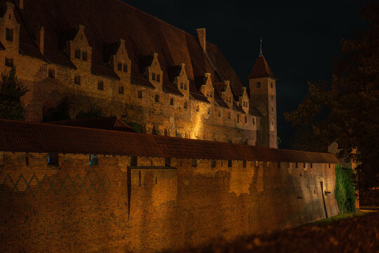 Malbork Castle at night in Poland with lit Gothic brick ramparts