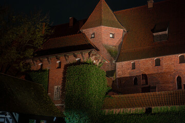 Night view of Malbork Castle, red brick walls and lit roofs in Poland © Earthly Shots