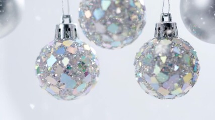 Hanging silver Christmas ornaments with glittery reflective surface against white background - Powered by Adobe