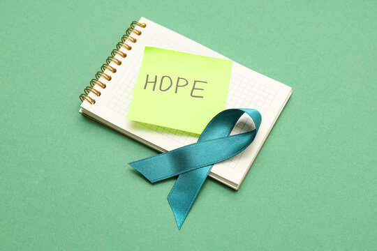 Teal ribbon and notebook with text ME TOO on green background. Sexual Assault Awareness Month - Powered by Adobe